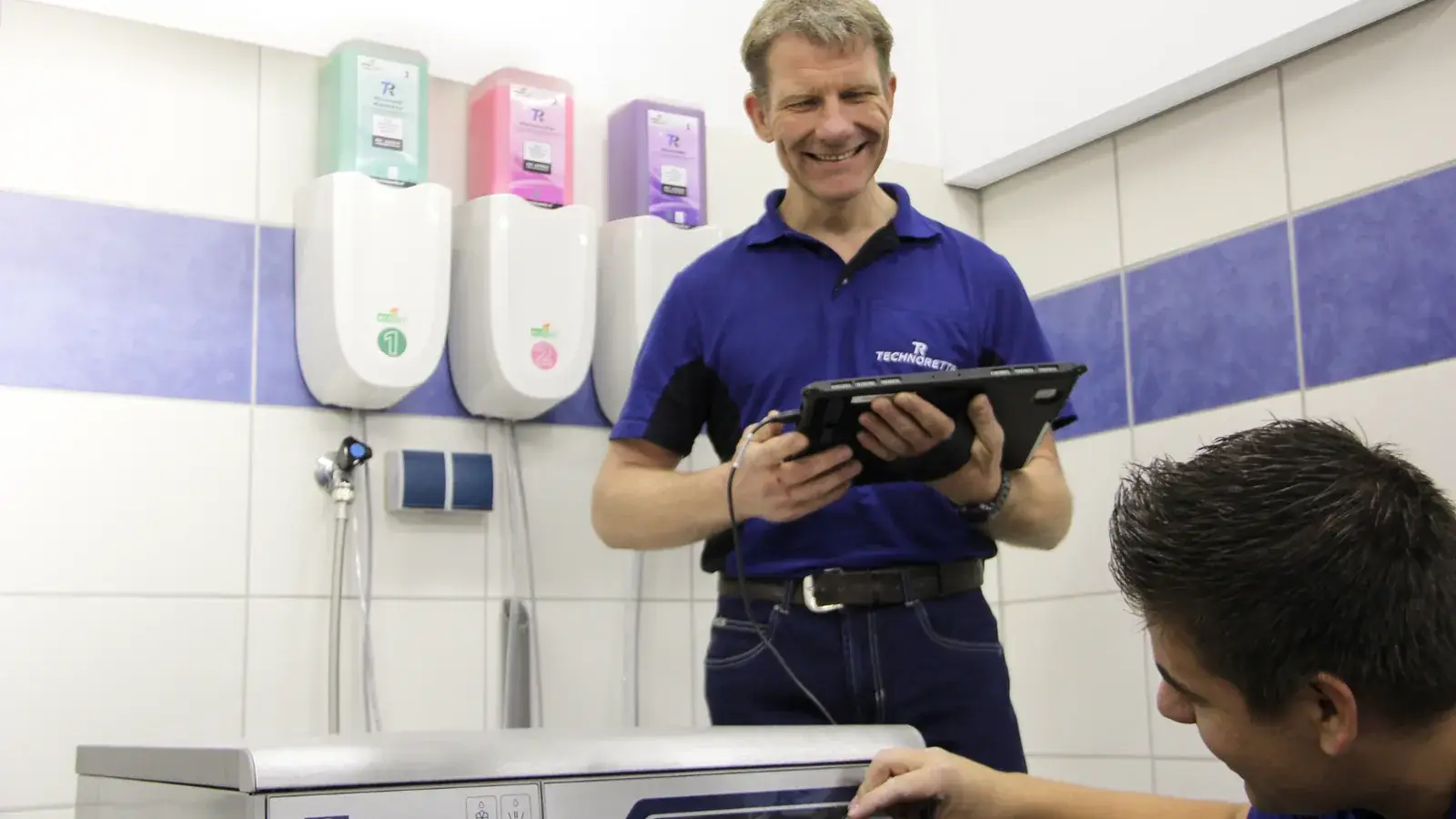 Twee monteurs van Technorette bij een professionele wasmachine met doseerinstallatie